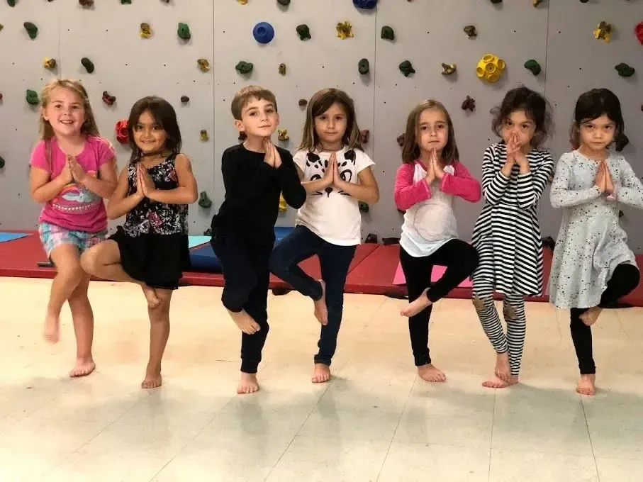 Children balancing in tree pose, hands at the heart