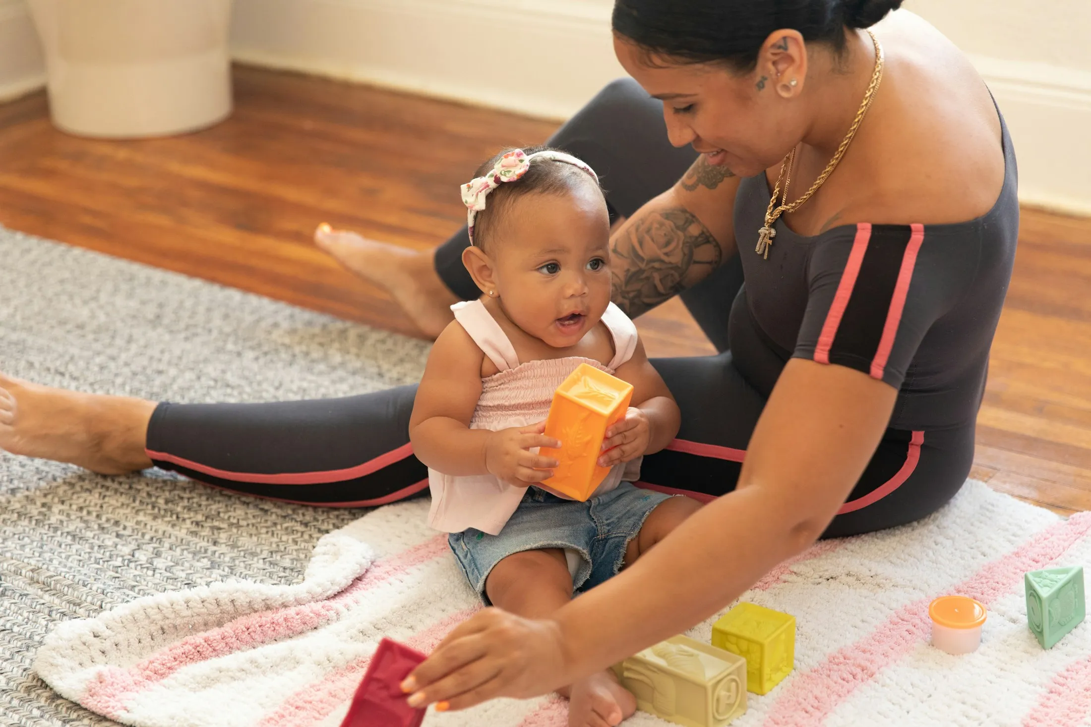 A mother playing with her baby daughter on a soft rug
