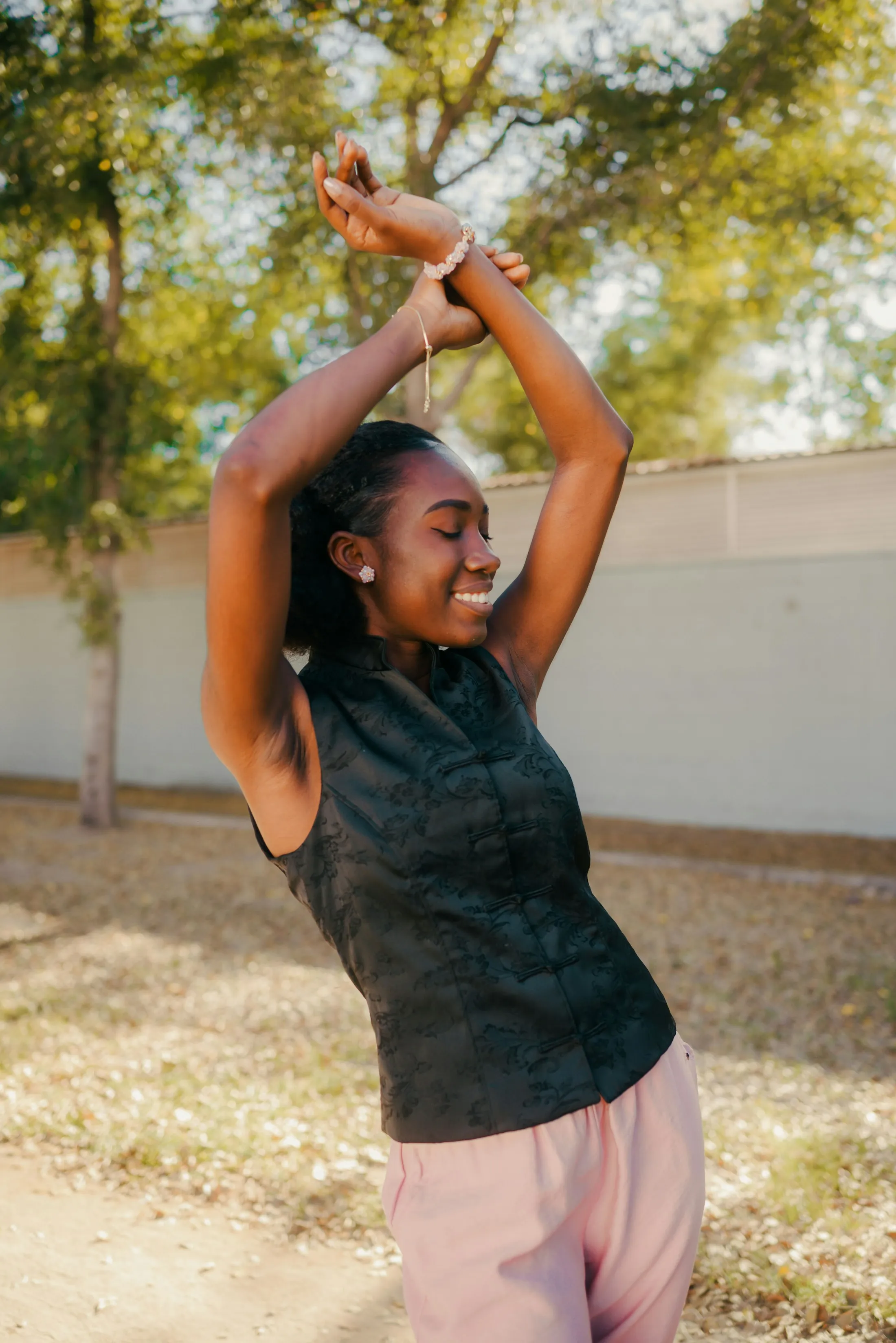 A young woman stretching her arms overhead, eyes closed, smiling