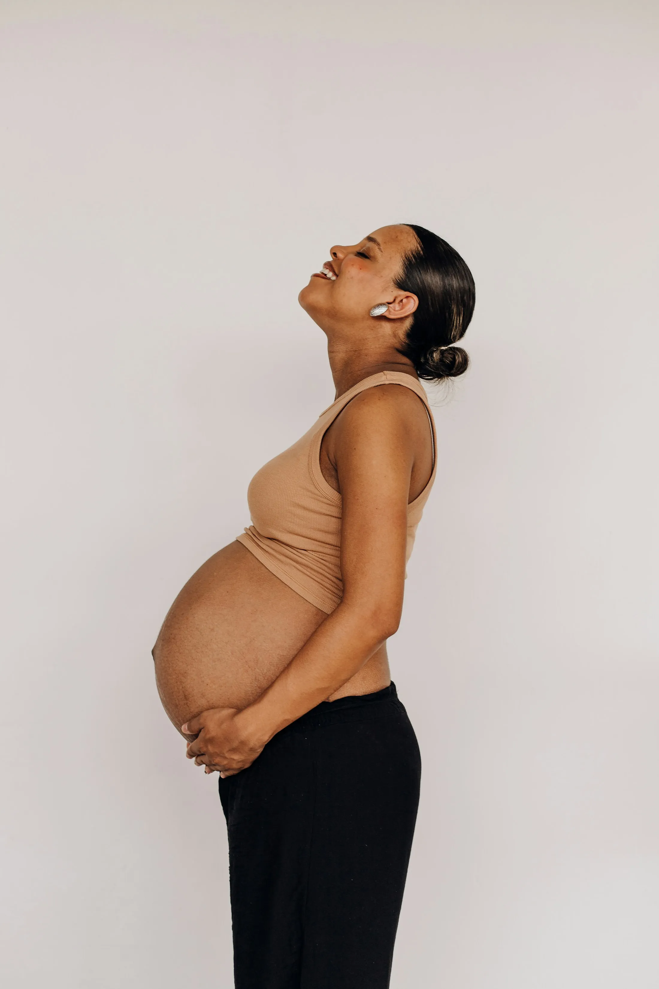 A pregnant woman smiling with her face turned up to the light